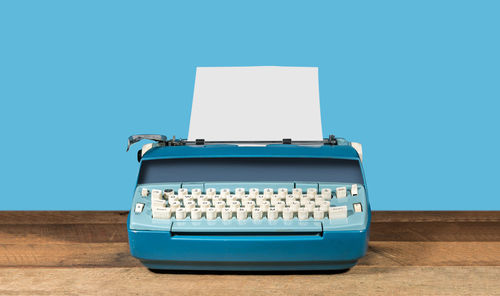 Telephone booth on table against blue wall