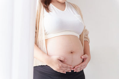 Midsection of pregnant woman measuring abdomen