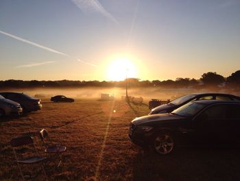 Car on field against sky during sunset