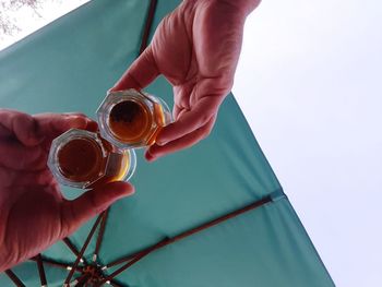 Close-up of hand holding drink against sky