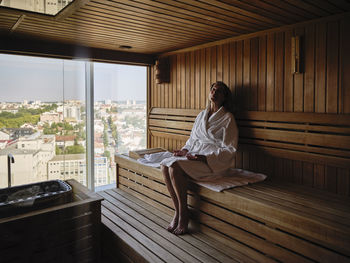 Relaxing senior woman sitting on wooden sauna at health spa