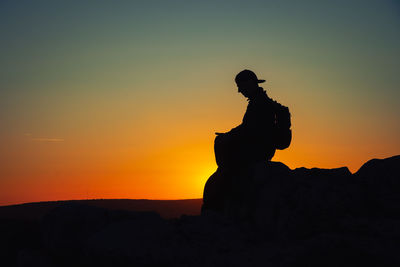 Low angle view of silhouette statue against orange sky
