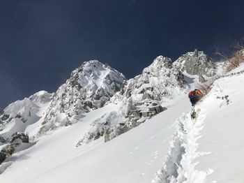 Low angle view of skiing on snowcapped mountain against sky