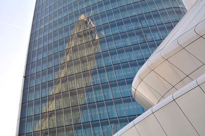 Low angle view of modern glass building against sky