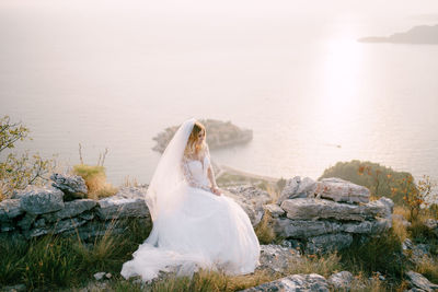 White swan on rock by sea against sky