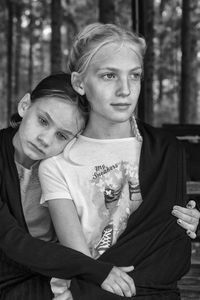 Girls sitting against trees in forest