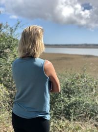 Rear view of woman standing on land against sky