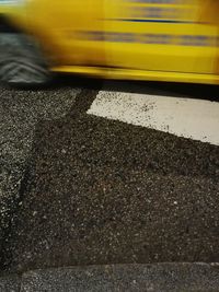 Close-up of yellow car on road