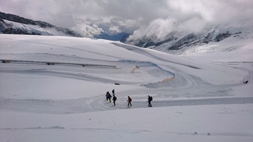 People skiing on snowcapped mountain against sky