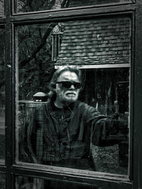 Portrait of young man standing by window