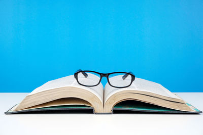 Close-up of open book on table against blue background