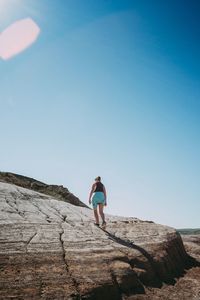 Full length of woman on rock against clear blue sky
