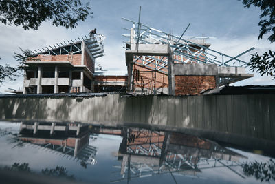 Reflection of under construction building on car roof against sky