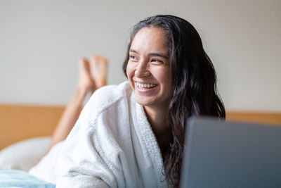 Happy woman surfing internet on laptop in bedroom at home