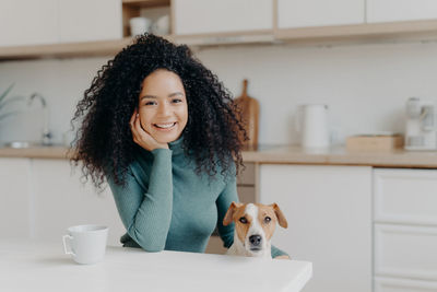 Portrait of smiling woman with dog at home