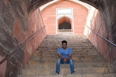 Portrait of man sitting on staircase of building