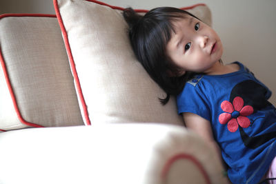 Portrait of cute girl sitting on sofa at home