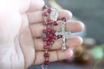 Person holding red rosary in hand. praying rosary concept.
