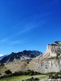 Scenic view of mountains against blue sky