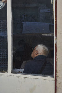Portrait of man looking through window