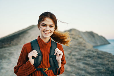 Portrait of smiling young woman standing against sky