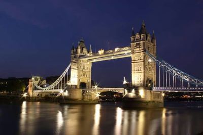 Illuminated bridge over river at night