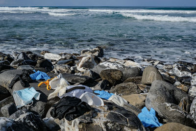 Medical waste,dirty used masks and plastic gloves garbage discarded on sea coast,covid19 pollution