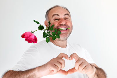 Midsection of person holding rose against white background