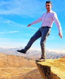 Full length portrait of man standing on cliff against sky