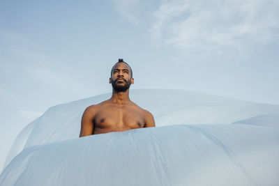 Shirtless mid adult man looking away while standing amidst foil