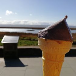 Close-up of ice cream cone against sea