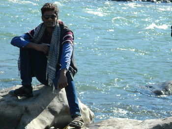 Low section of man with arms raised in sea