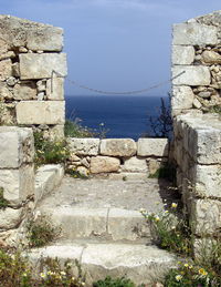 Stone wall by sea against sky