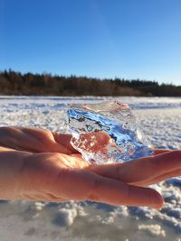 Midsection of person holding sea against clear sky