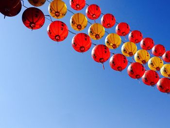 Low angle view of lanterns against clear blue sky