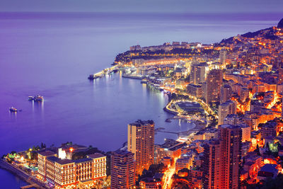 High angle view of cityscape by sea at night