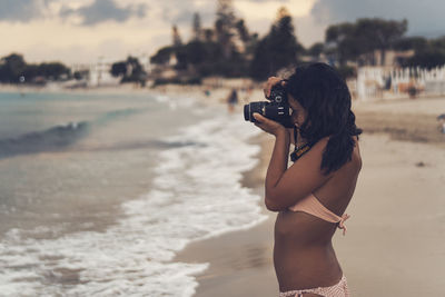 Rear view of woman photographing sea