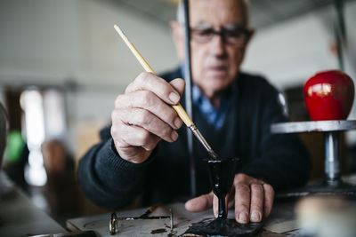 Senior man decorating ceramic in his spare time