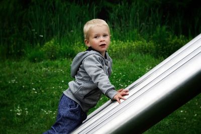 Cute boy looking away while standing on grass