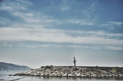 Lighthouse by sea against sky