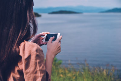 Midsection of woman using mobile phone in water