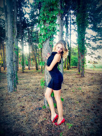 Young woman standing on tree trunk in forest