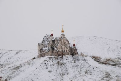 Traditional windmill on snow covered mountain against clear sky