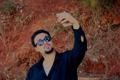 Young man wearing sunglasses while taking selfie with smart phone