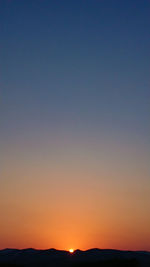 Scenic view of silhouette mountains against clear sky during sunset