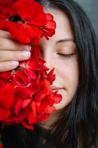 Close-up of woman holding red geranium flower