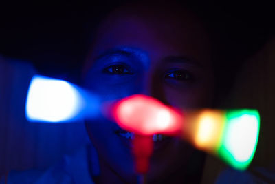 Close-up portrait of mid adult woman at night with light glare