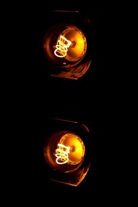 Close-up of illuminated light bulb over black background