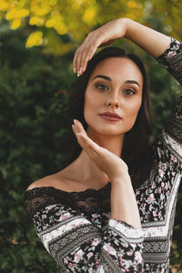 Portrait of young woman gesturing against plants