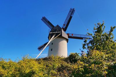 Low angle view of traditional windmill against clear blue sky